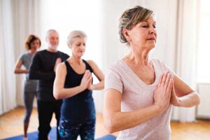 senior adults practice yoga poses in their senior yoga therapy
