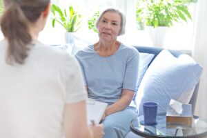 a senior woman sits and listens to her occupational therapist in her senior occupational therapy program