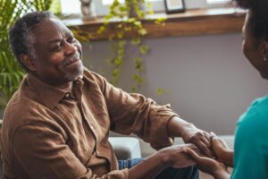a senior man holds a nurses hand for support during his dementia patient care