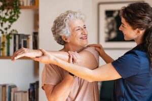 a physical therapist helps a senior woman with some exercises so she can experience physical therapy benefits